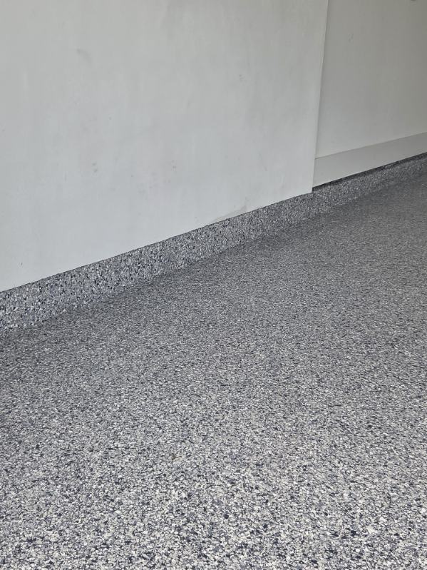Close-up of gray flake epoxy floor with coved base along the wall